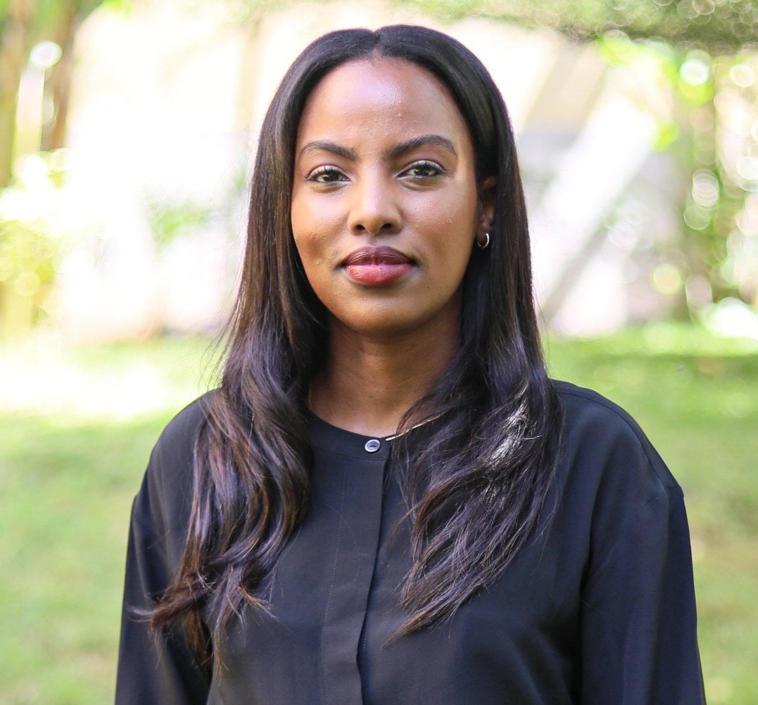 A Black woman with long hair wears a black blazer