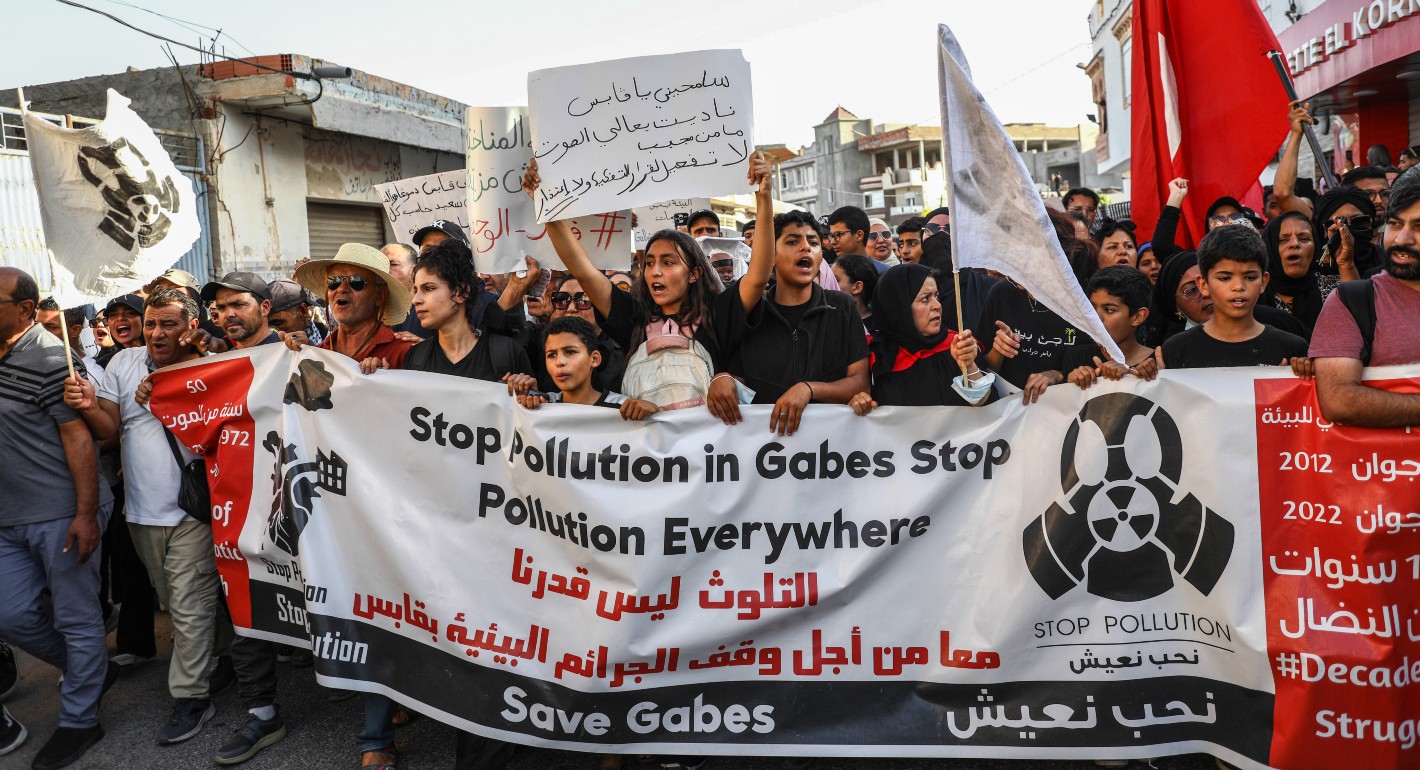 Teenagers hold a large banner reading "stop pollution in Gabes, stop pollution everywhere, save Gabes'' in English and Arabic