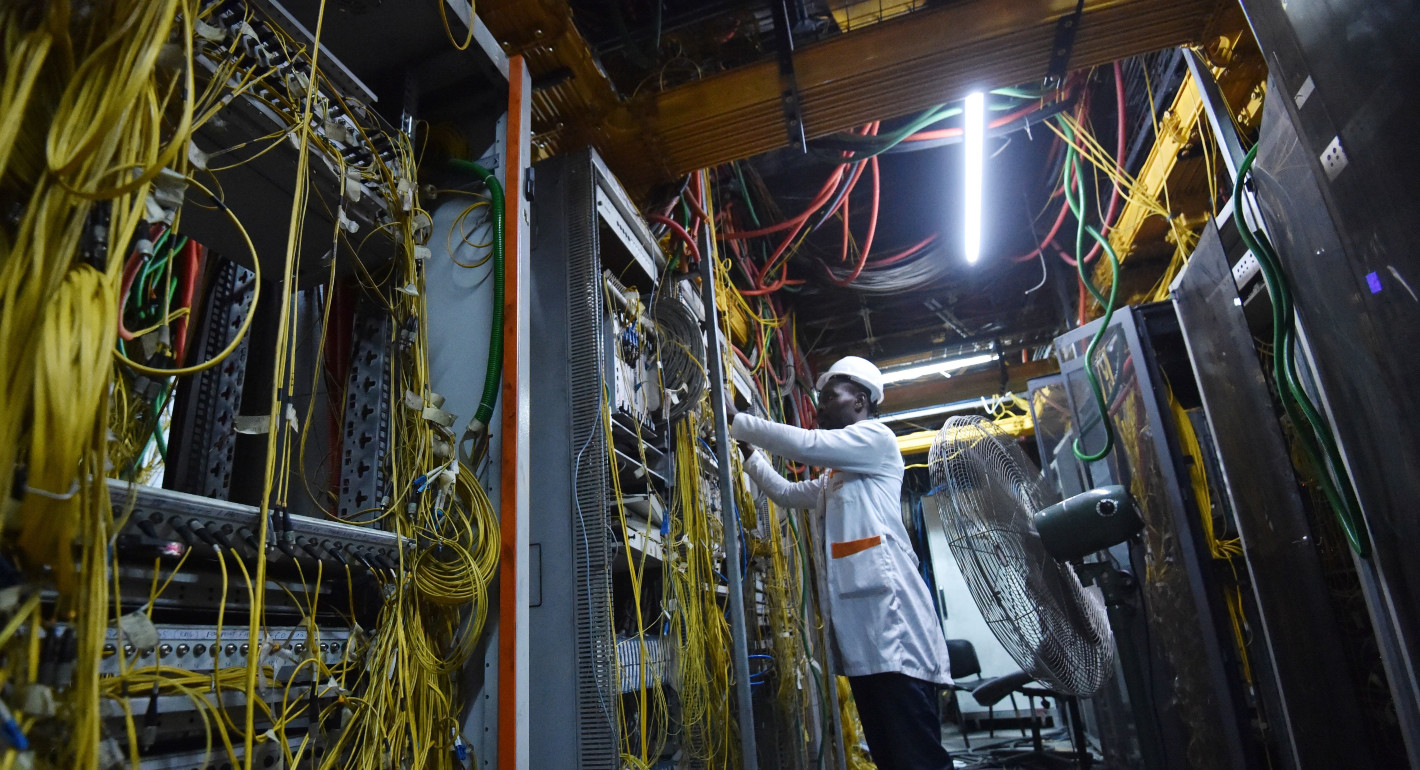 Photo of a man conducting repairs in a technical center, surrounded by wires.