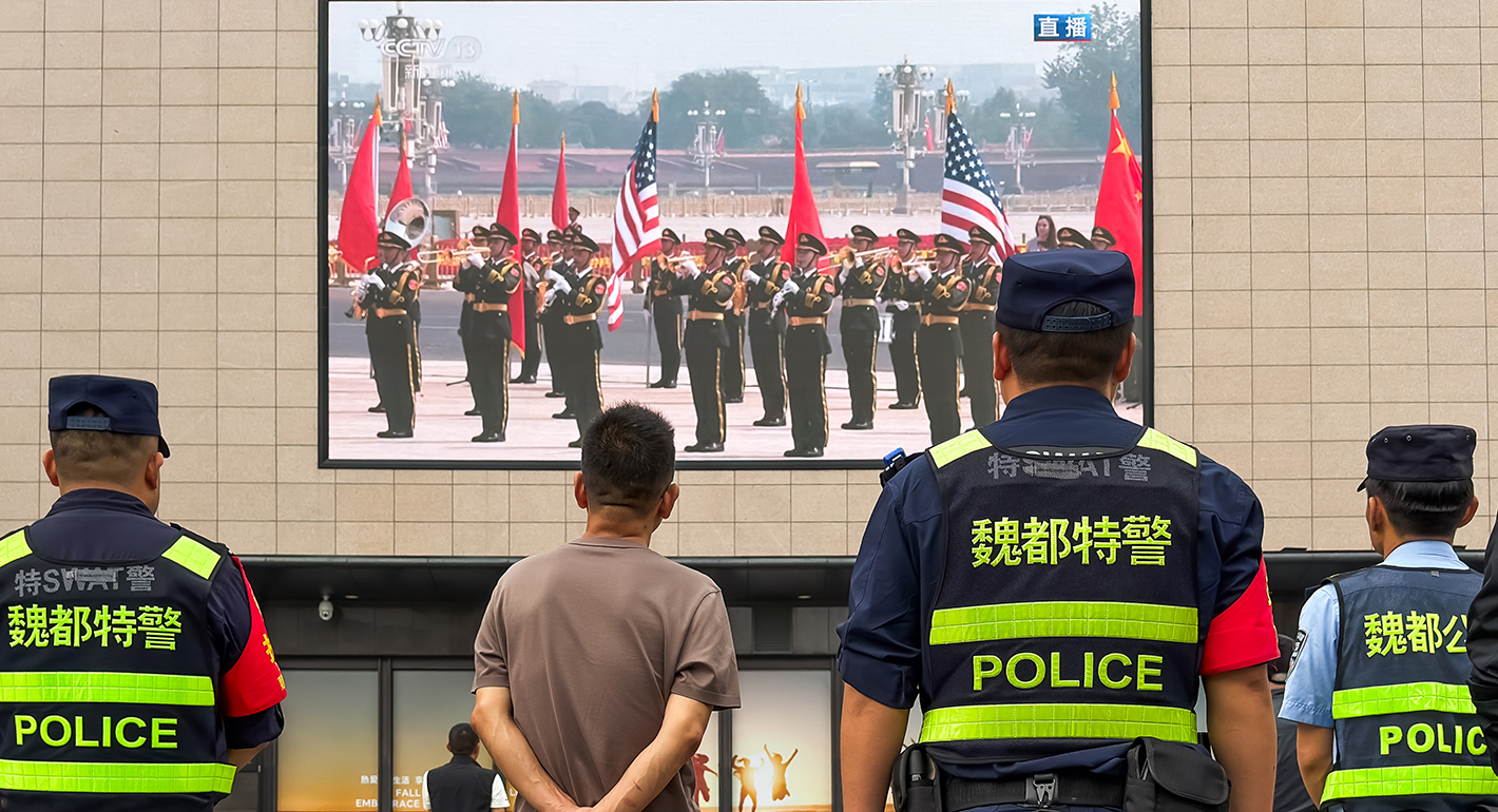 olice officers and residents stand in front of a shopping mall while a large outdoor screen broadcasts a military welcome ceremony featuring U.S. and Chinese flags for U.S. President Donald Trump hosted by Chinese President Xi Jinping at the Great Hall of the People on May 14, 2026