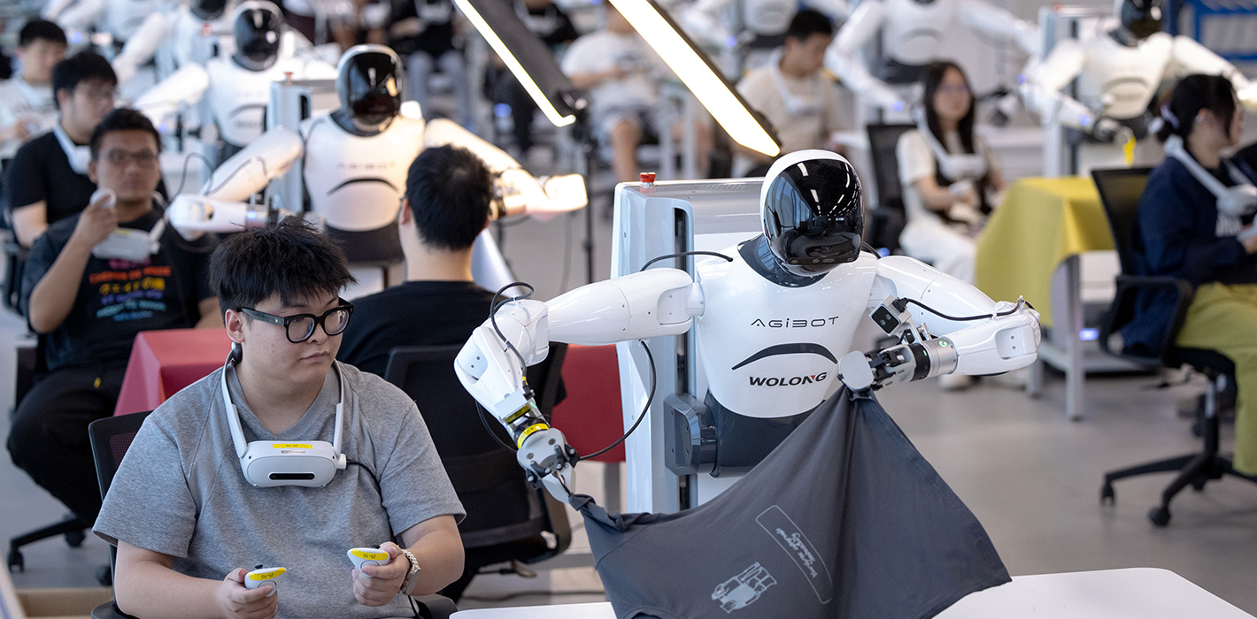 Humanoid robots follow technicians to learn job skills at the data collection area of an embodied AI robot innovation center on September 14, 2025 in Shaoxing, Zhejiang Province of China. 
