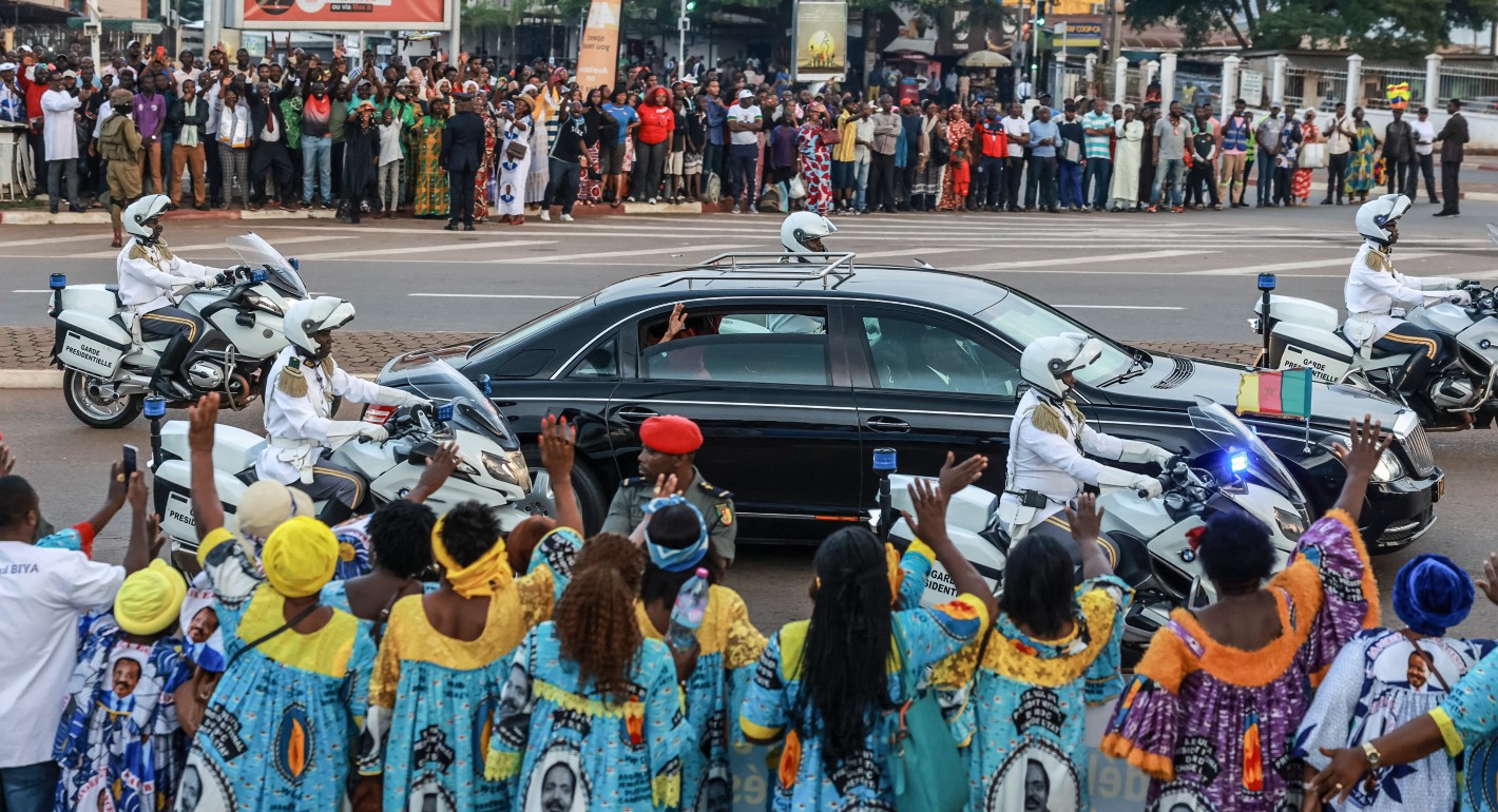 People waving to a passing car surrounded by motorcycles