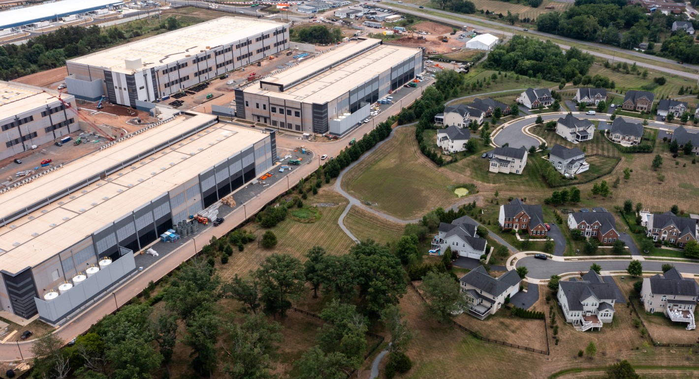 Aerial view of large data center buildings next to single-family houses