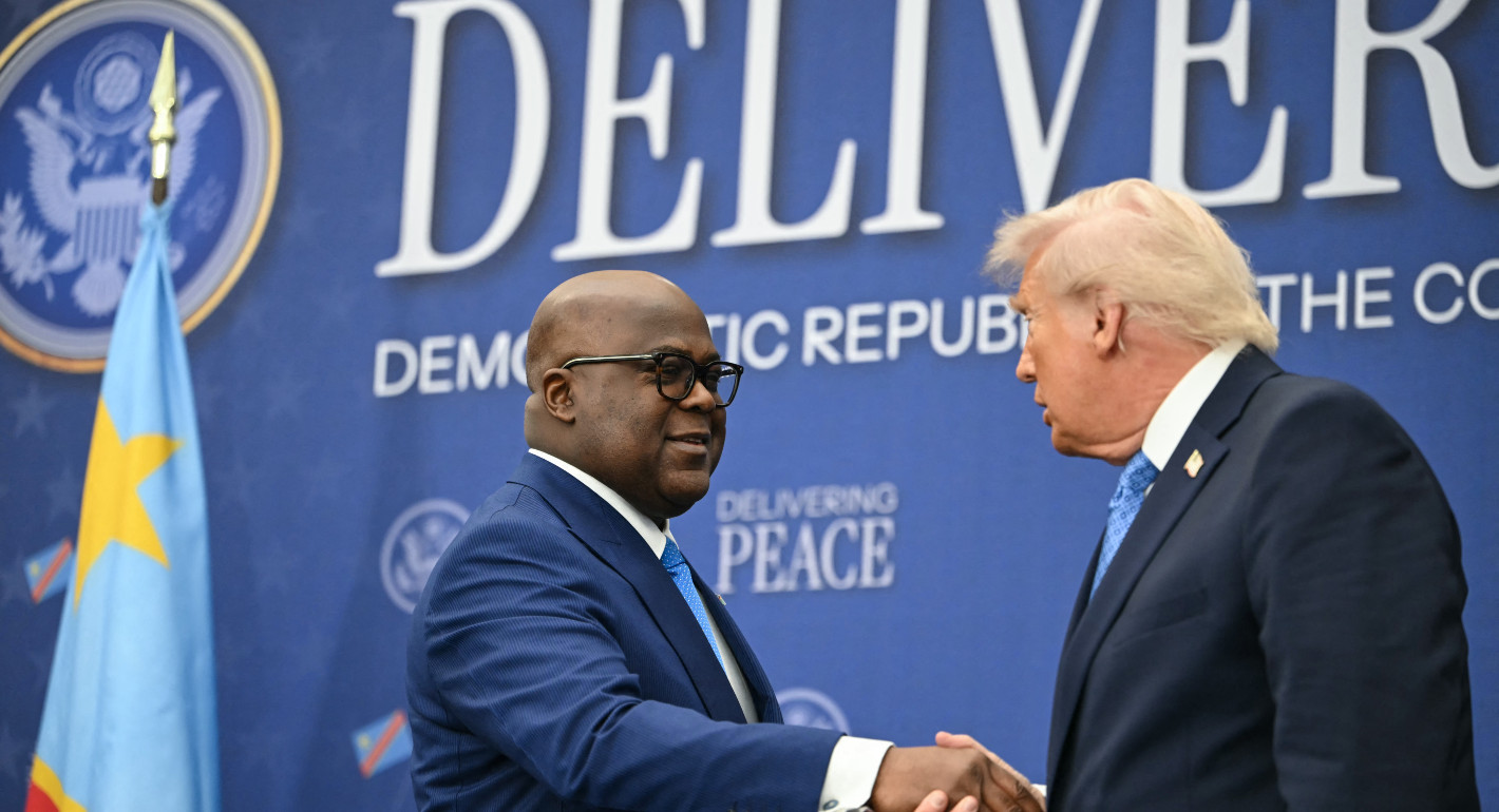 Photo of Donald Trump and Felix Tshisekedi shaking hands in front of a blue banner.