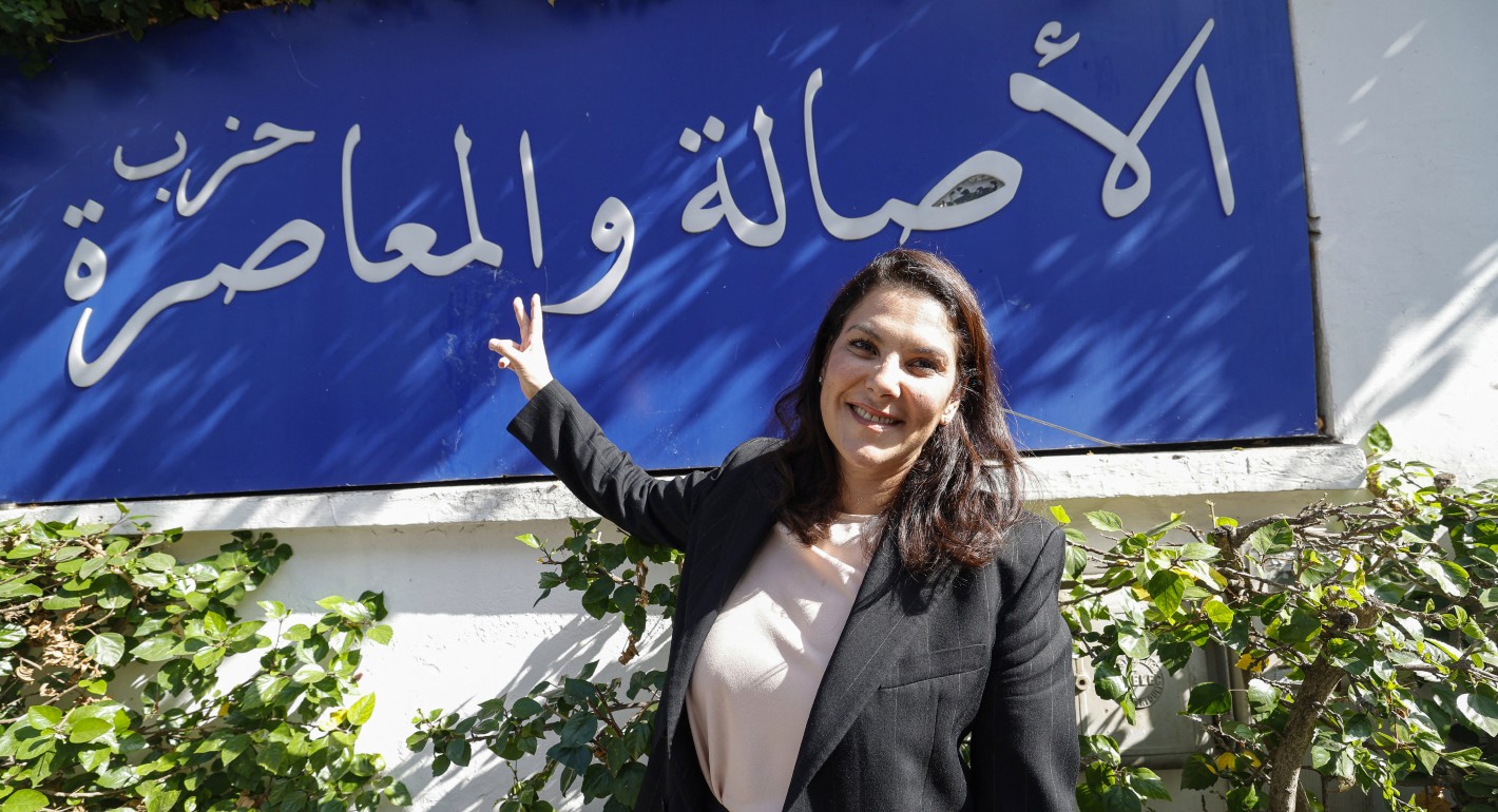 Woman flashing a peace sign in front of a blue sign