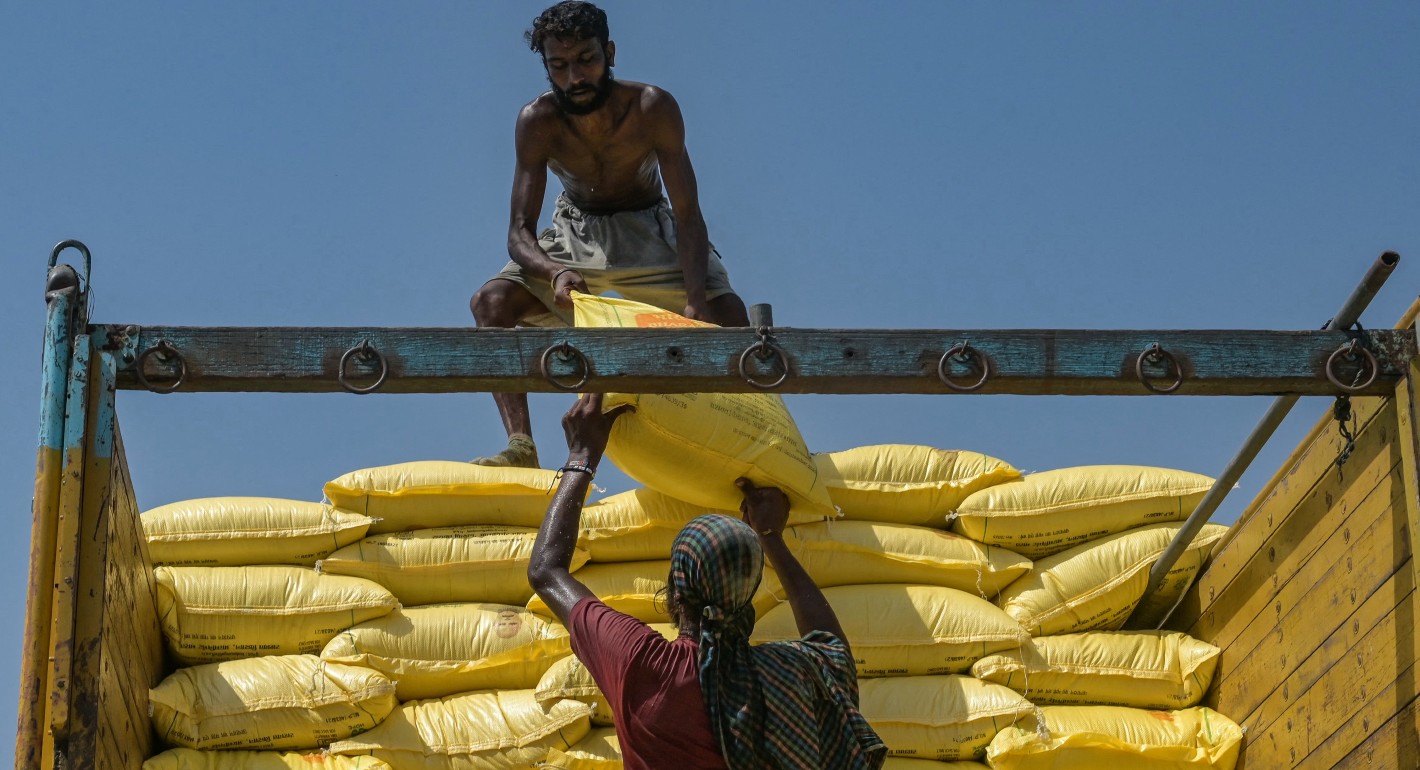 One man tossing a sack to another to stack on a truck