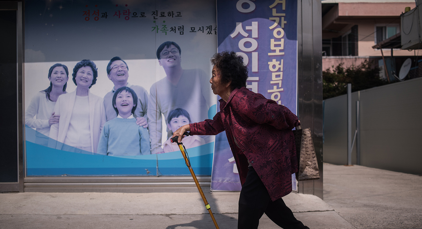 An elderly woman walks past a poster at a health centre in Gunwi, some 200 kilometres south of Seoul