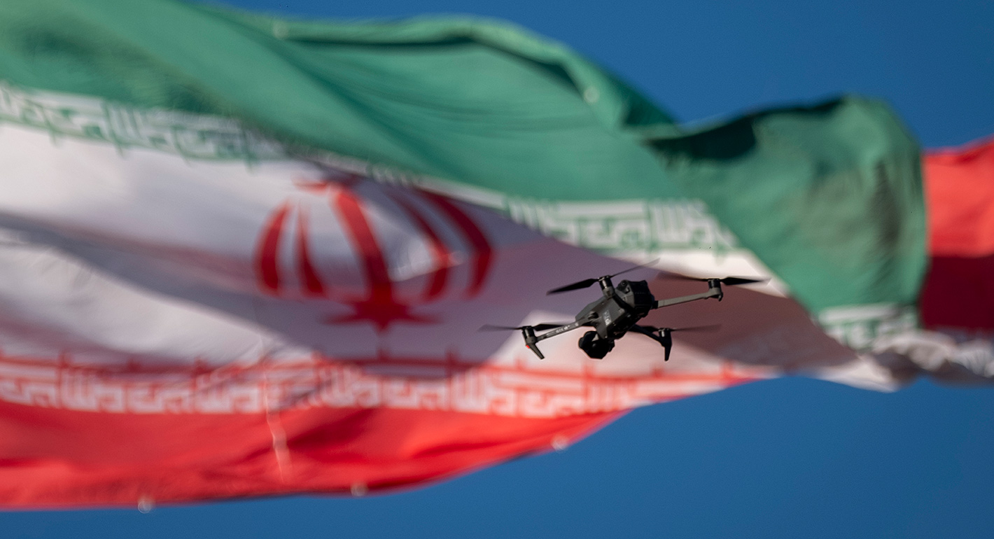 A drone flies in front of an Iranian flag in southern Tehran, Iran
