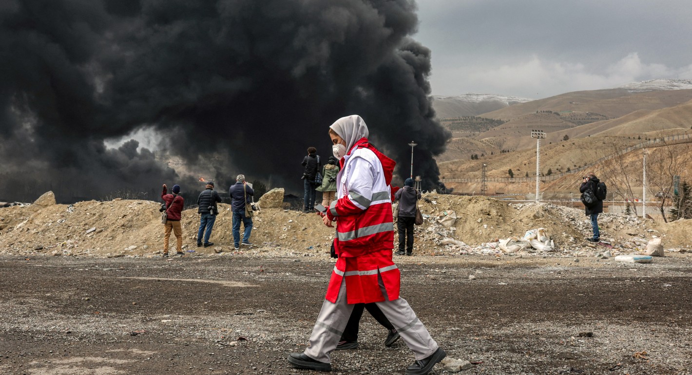 Two women walking in front of thick black smoke