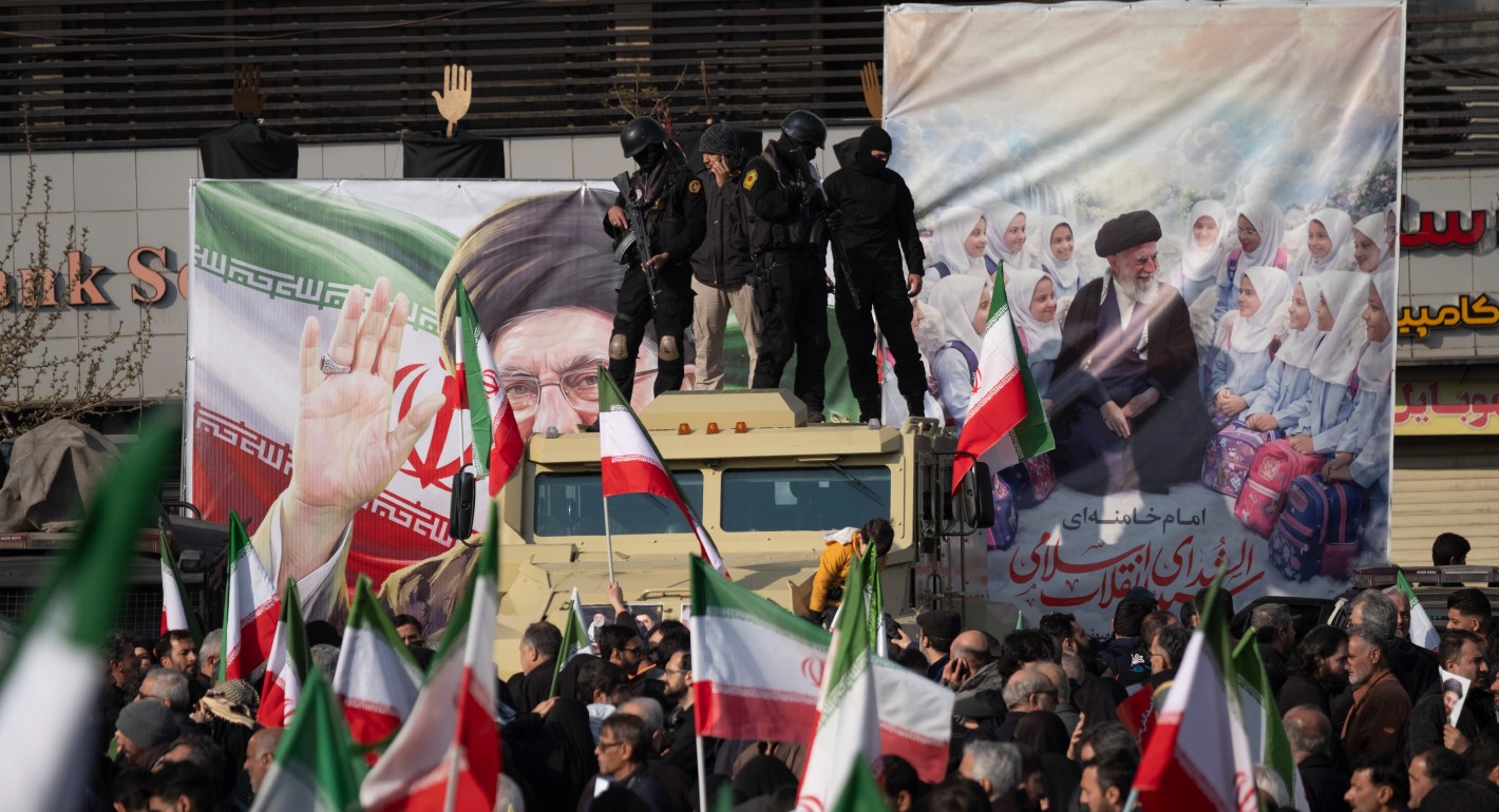 Heavily armed security personnel standing atop an armored vehicle