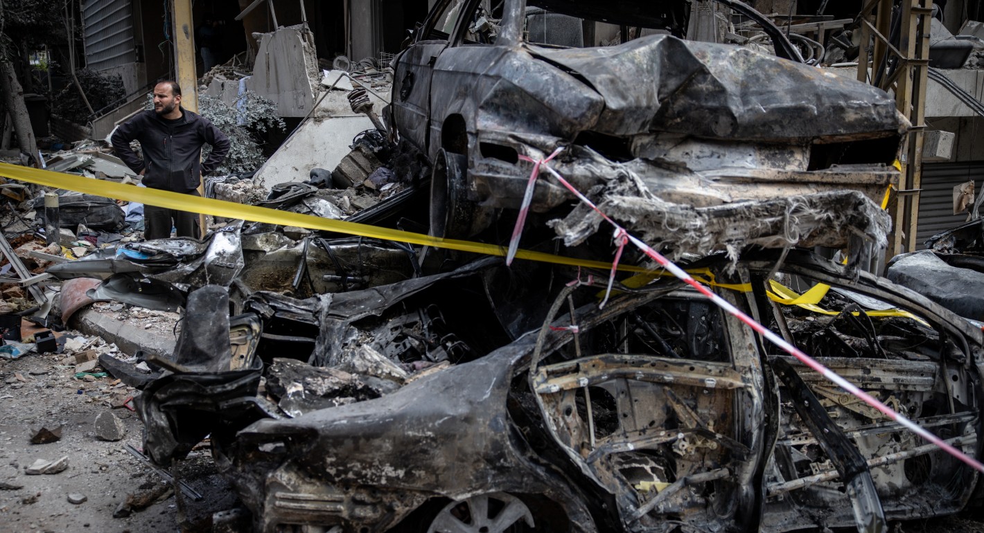 Man standing next to a pile of burned cars