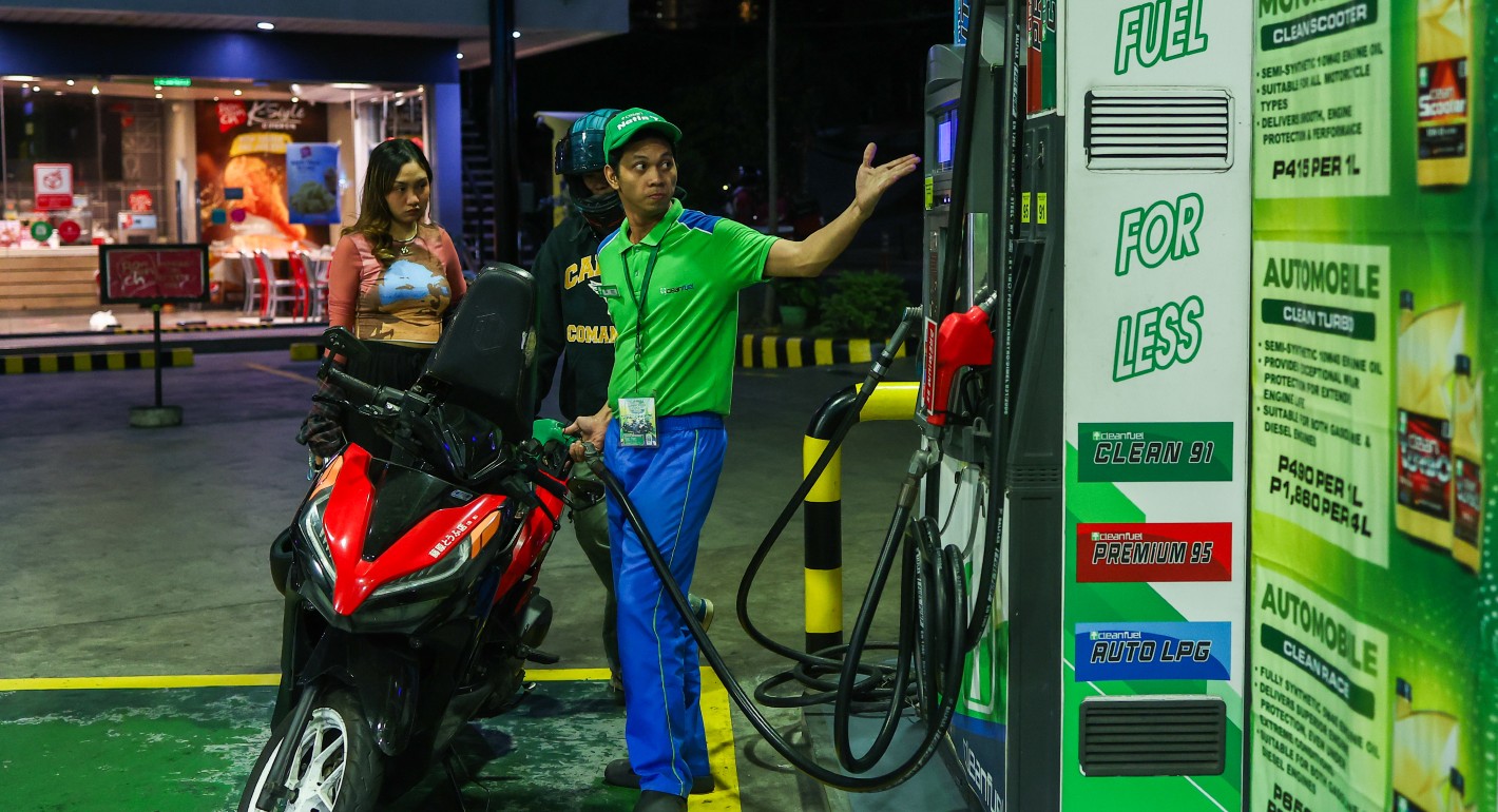 Gas station attendant gesturing while a woman gets her motorcycle refilled