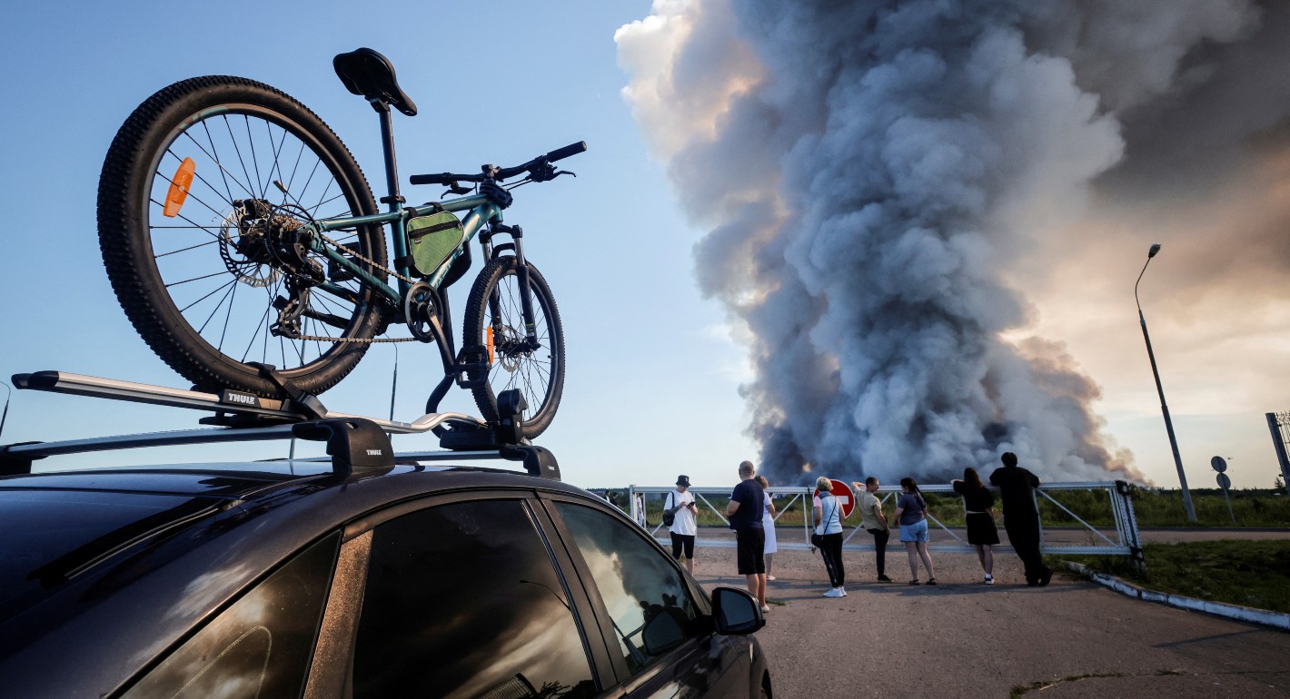 people watching a huge column of smoke in the distance