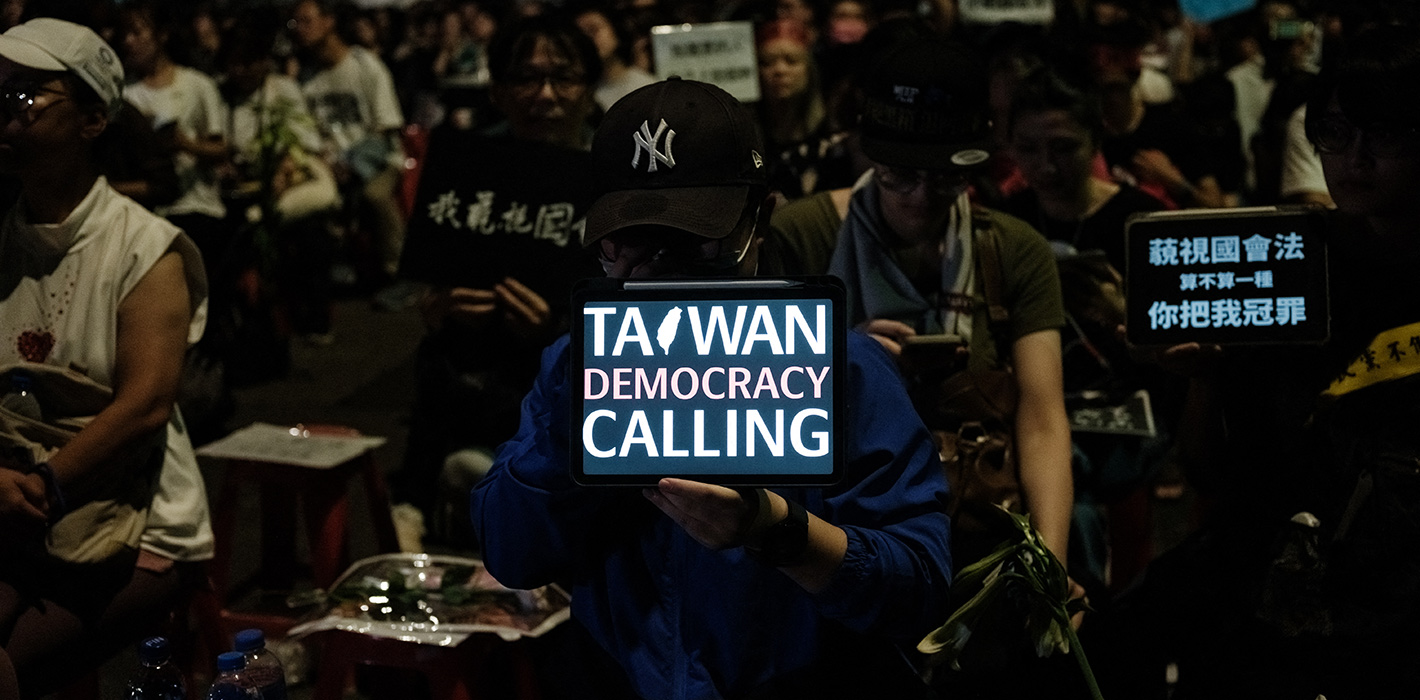 A demonstrator holds a tablet displaying a message as they occupy a road in protest against plans by the main opposition Kuomintang (KMT) and the Taiwan People's Party (TPP) to expand the parliamentary powers during the vote for the Parliament reform bill, outside the Parliament in Taipei on May 24, 2024. T