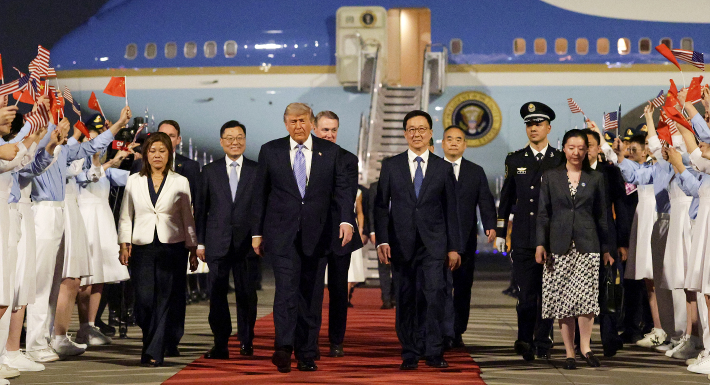 Trump and others walking down a red carpet, with Air Force One in the background