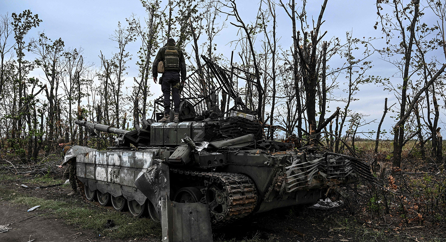 A Ukrainian soldier on top of a Russian tank