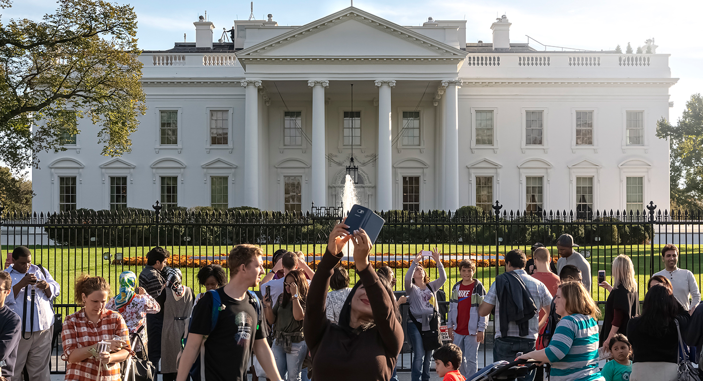 Tourists taking photos in front of the White House on a sunny day