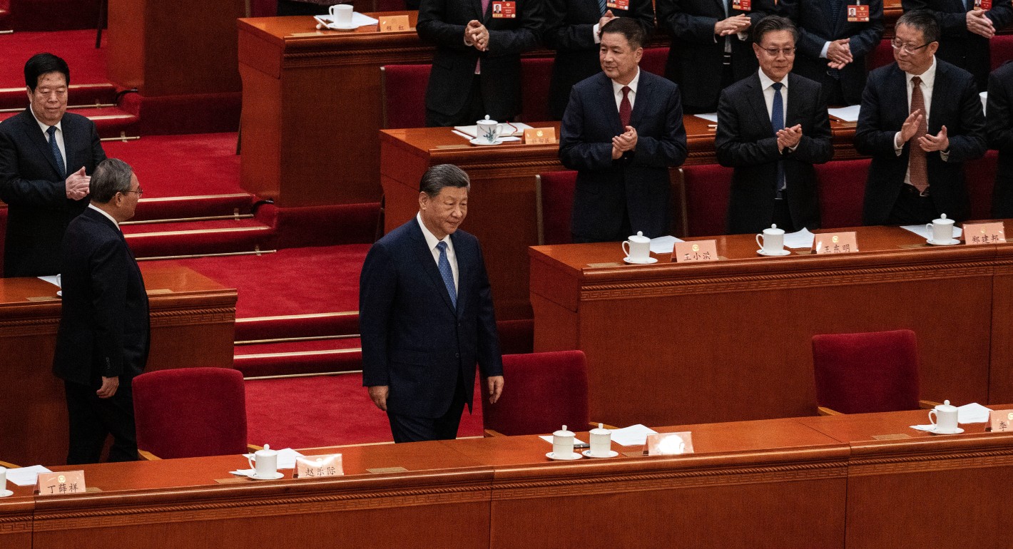 Xi walking into a room with people standing and applauding around him