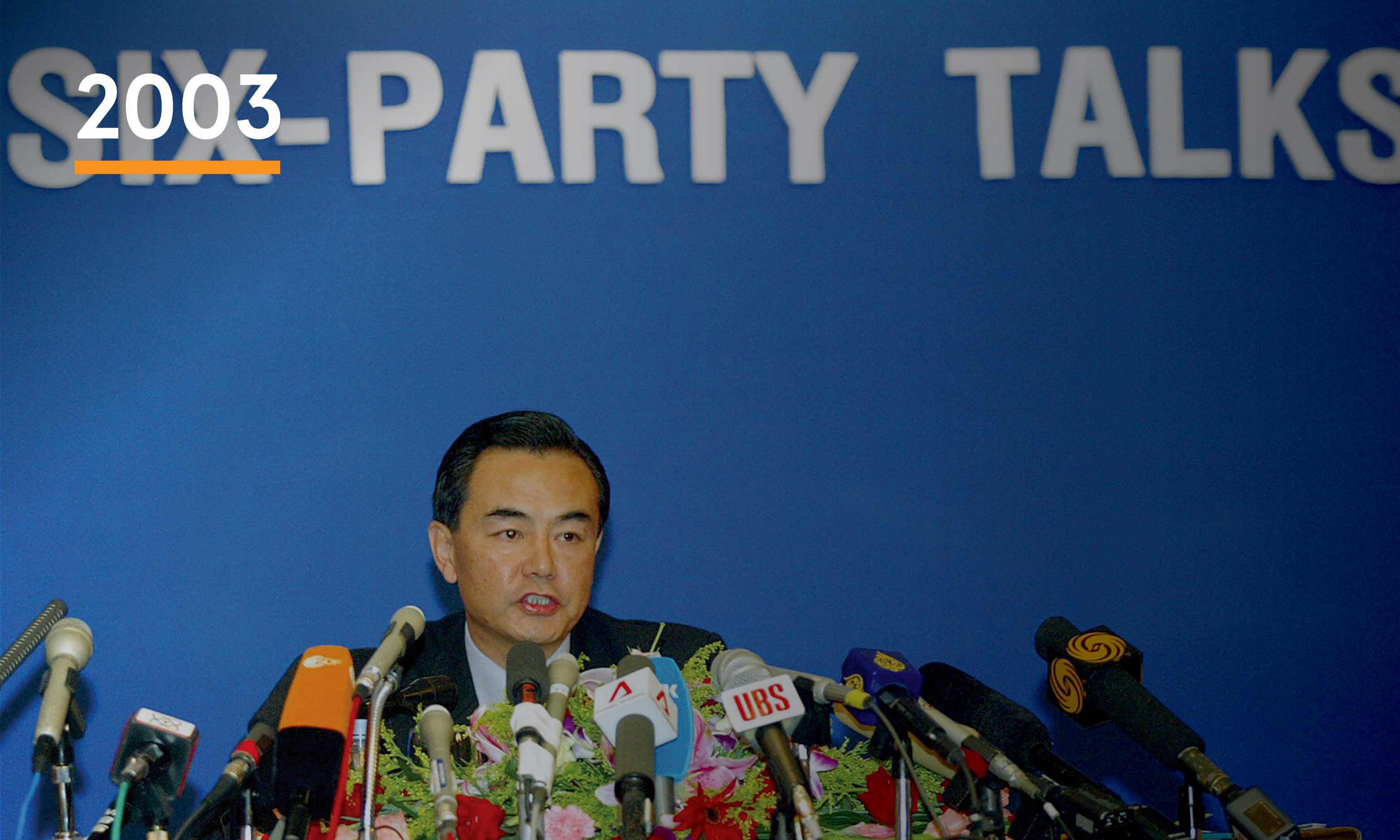 A man in front of a well of microphones