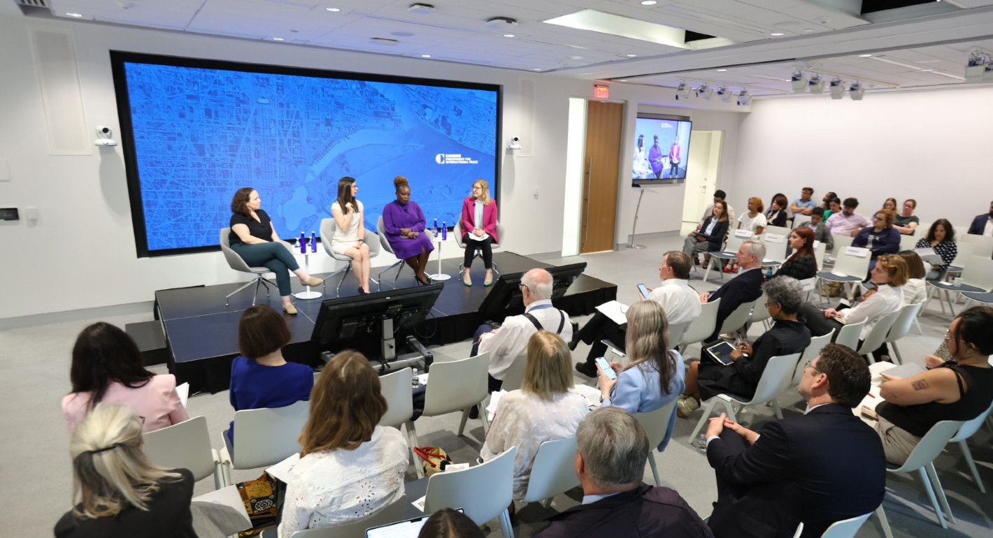 People sitting in a conference room watching four people on a panel