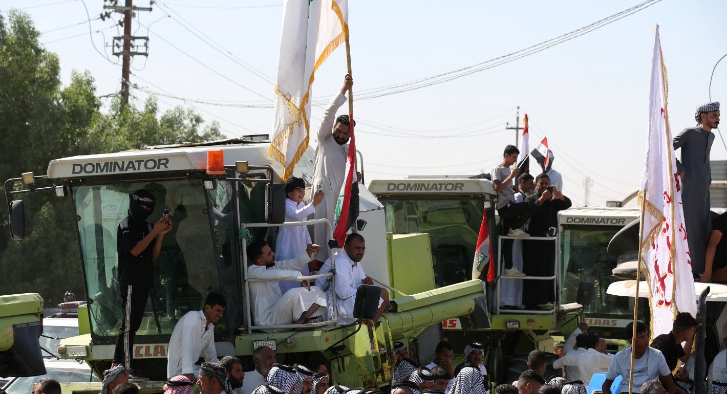 A man stands on a truck holding a flag above a crowd