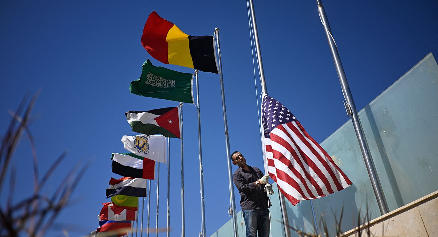 A municipal employee raises the US flag among those of other nations in Sharm el-Sheikh, as the Egyptian Red Sea resort town gets ready to receive international leaders, following a Gaza ceasefire agreement, on October 11, 2025.