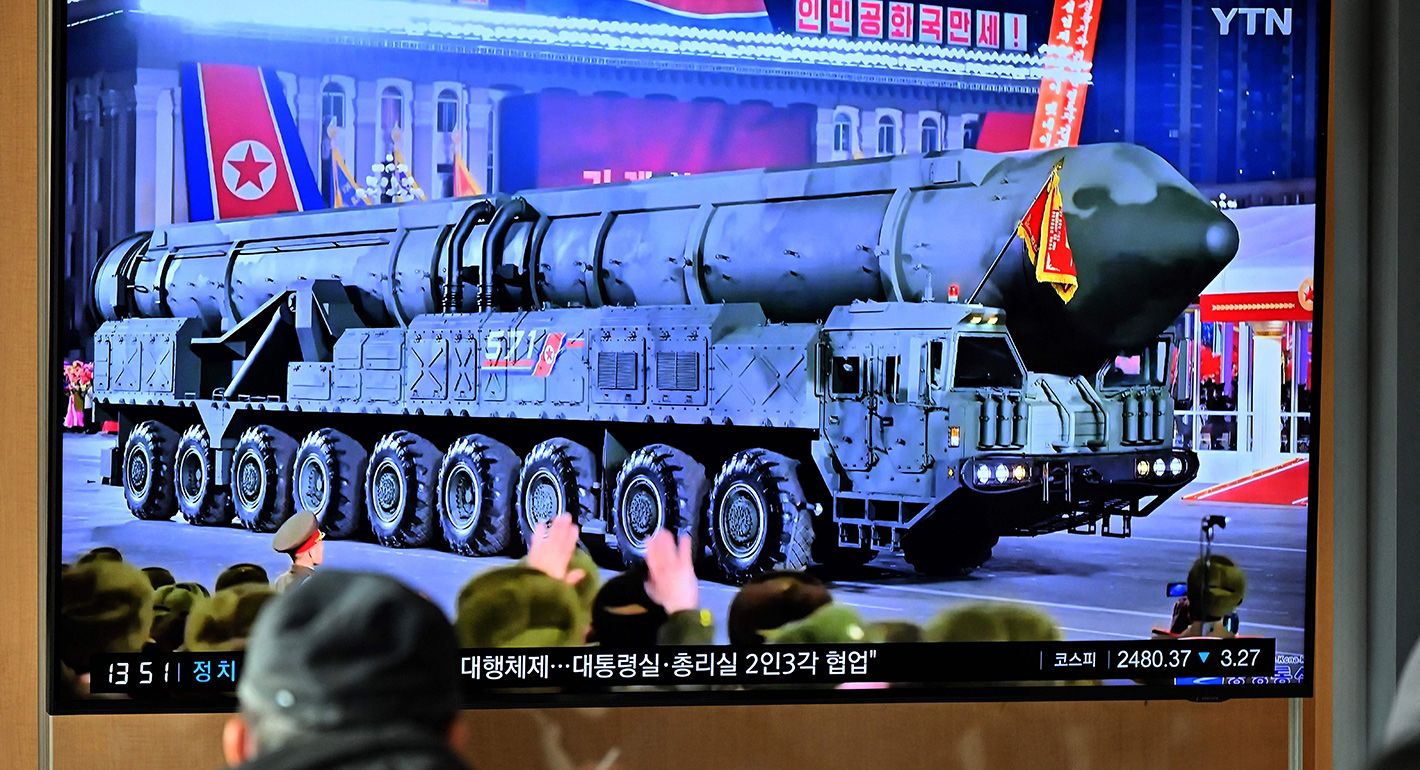 A man watches a television screen showing a news broadcast with an image of a North Korean military parade held in Pyongyang to mark the 75th founding anniversary of its armed forces, at a railway station in Seoul on February 9, 2023