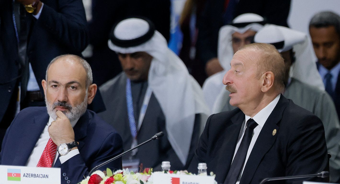 Two men in suits sitting next to each other at a meeting