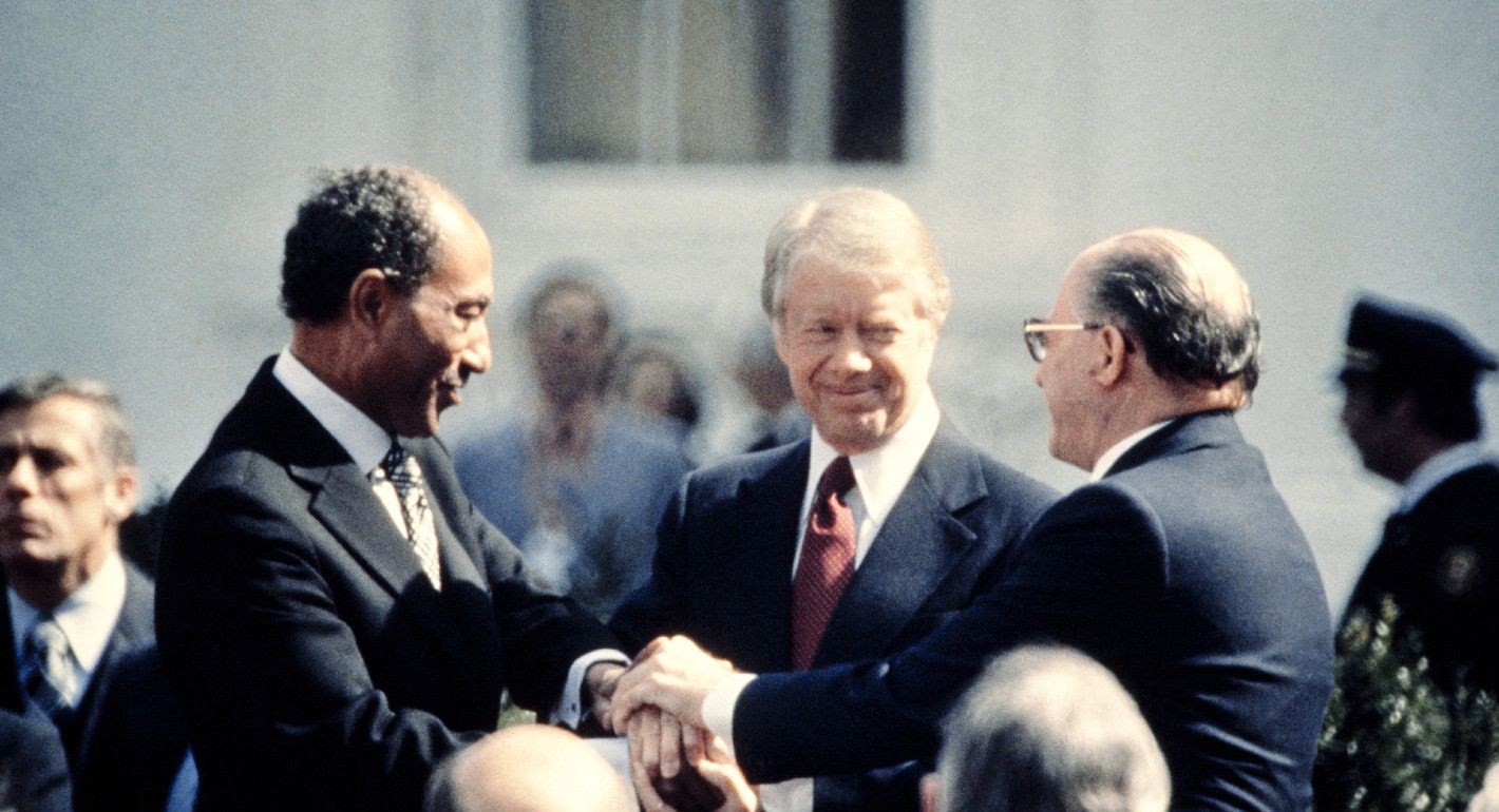 Photo of U.S. president Jimmy Carter, Egyptian president Anwar Sadat, and Israeli prime minister Menachem Begin shaking hands.