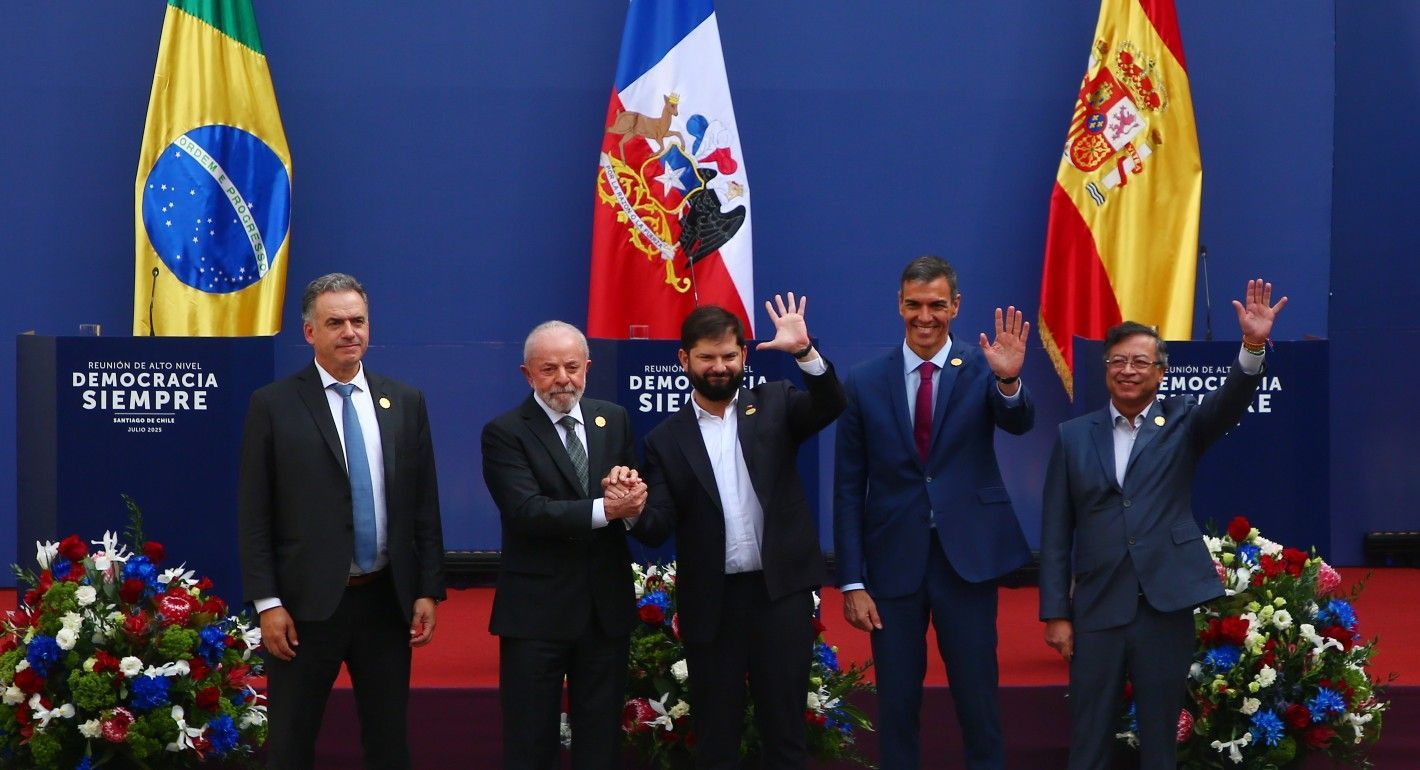 five men standing in a line in front of flags