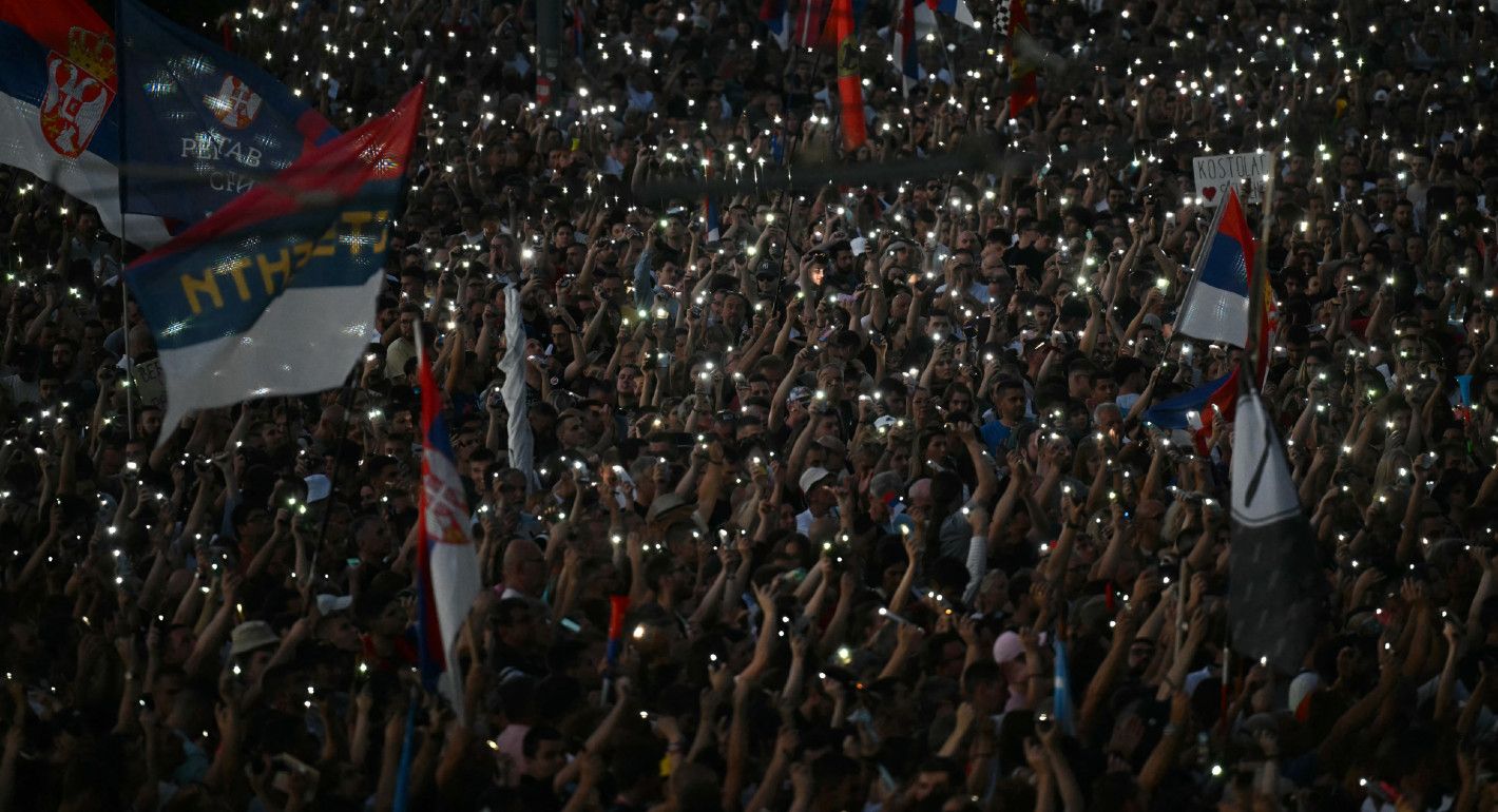 Photo of a crowd of protesters holding up cellphone lights together in the dark.