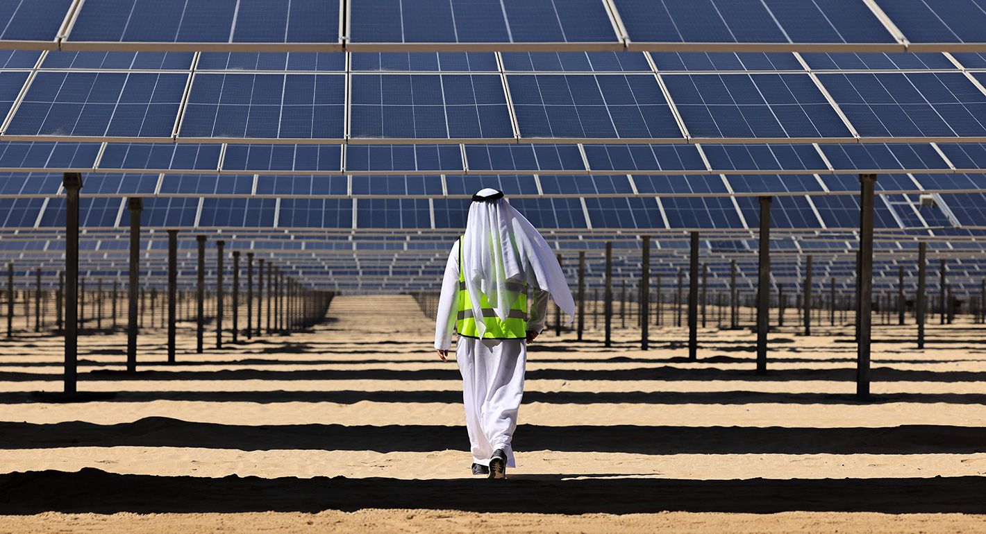 An Emirati man walks beneath photovoltaic panels at al-Dhafra Solar Photovoltaic (PV) Independent Power Producer (IPP) project south of the capital Abu Dhabi, on November 13, 2023.