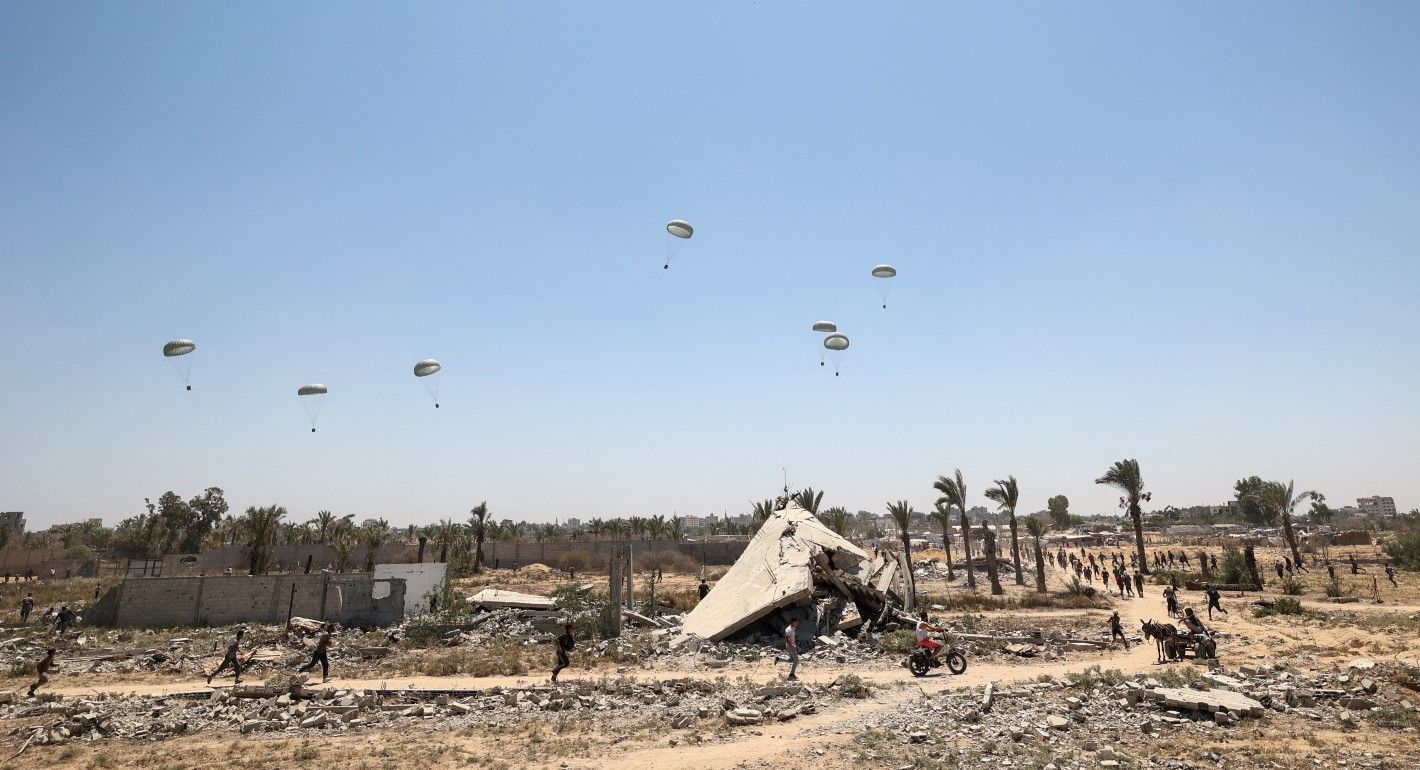 people running amid rubble to air-dropped aid