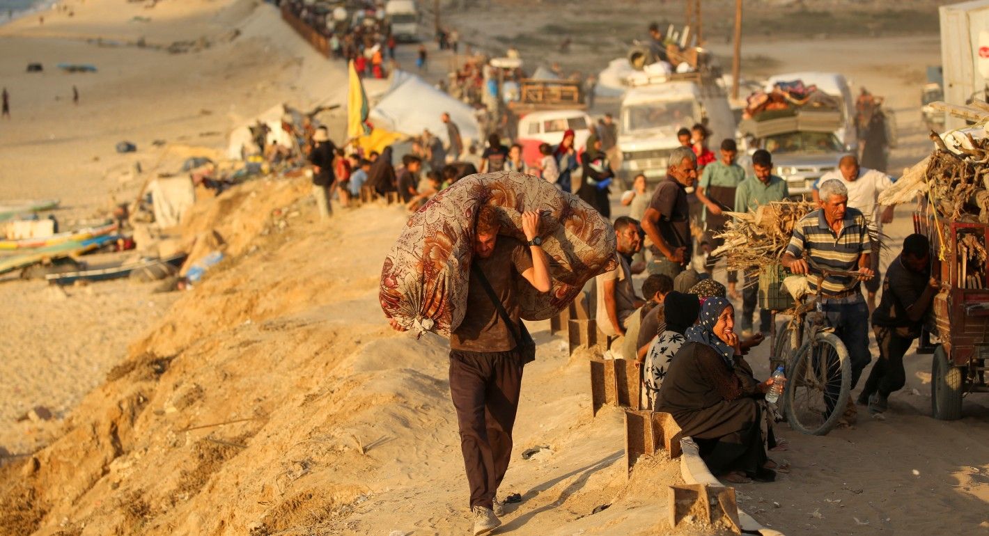 Person carrying a mattress alongside other vehicles driving with belongings
