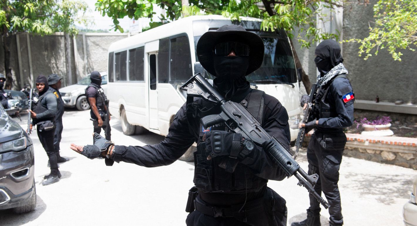 Masked and armed officer gesturing toward the camera