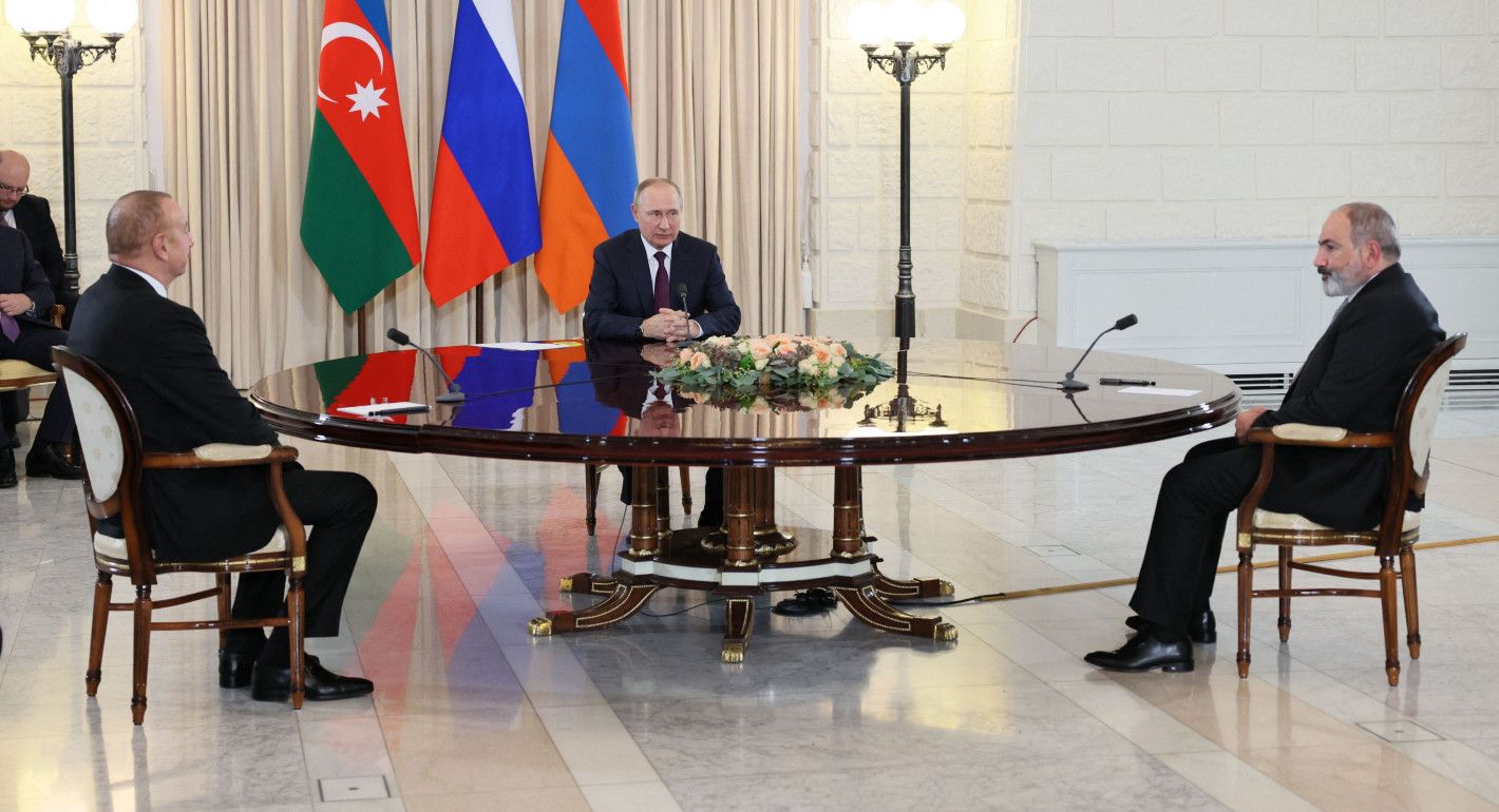 three men sitting around a large circular table