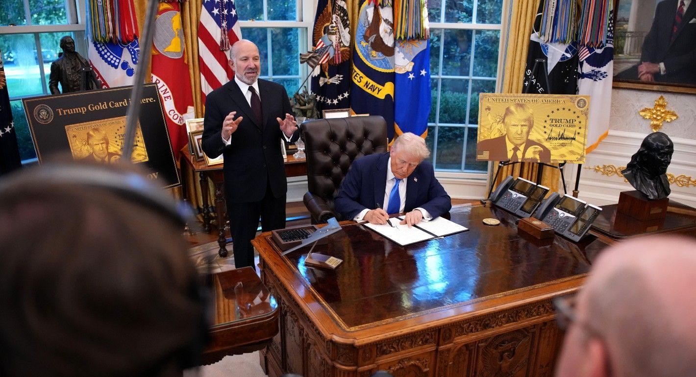 Trump at a desk signing a piece of paper