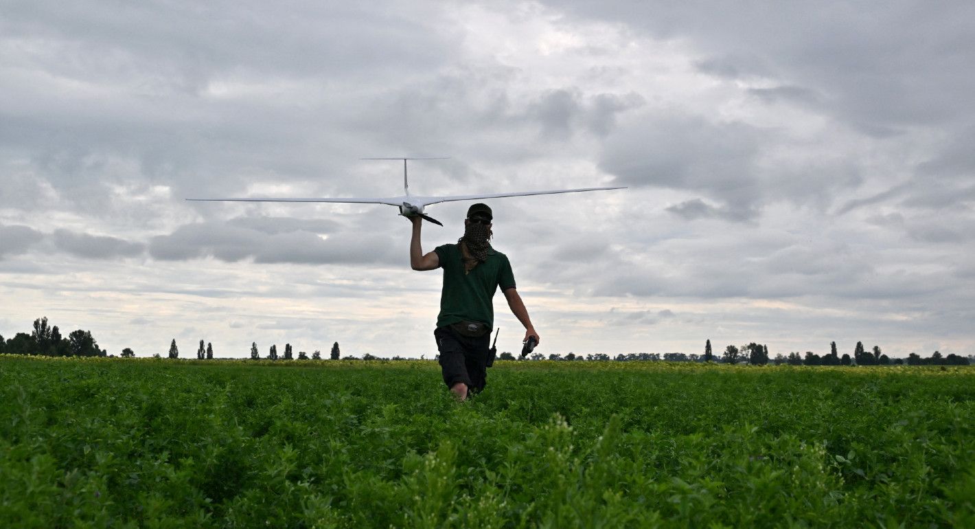 Photo of an operator carrying an airstrike drone through a field in Ukraine.