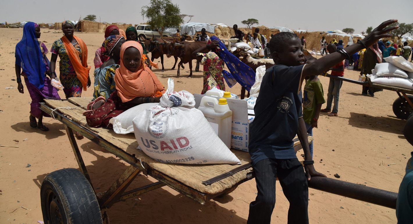 Kids on a wagon with food supplies with the USAID logo