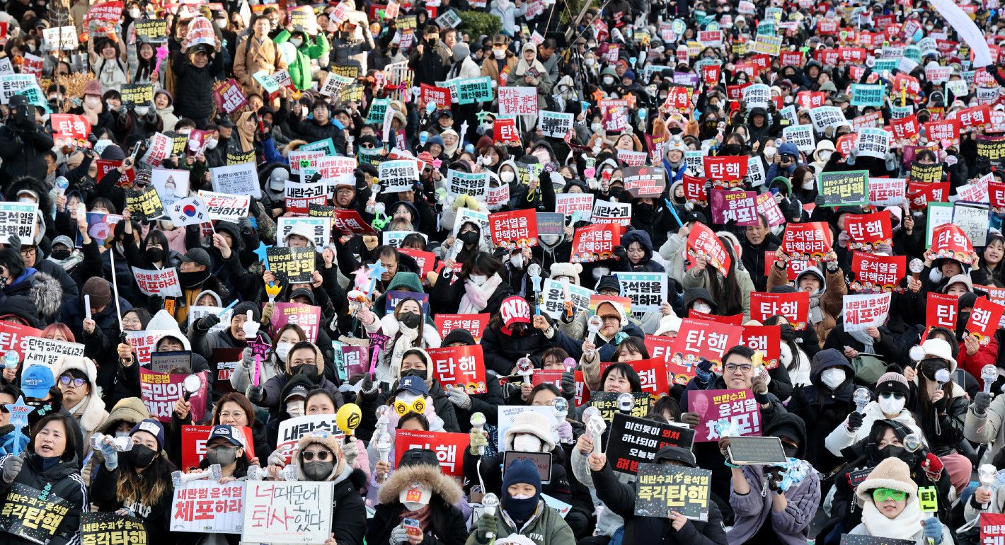 Photo of protesters at a rally holding signs in Korean calling for the impeachment of Yoon Suk Yeol.